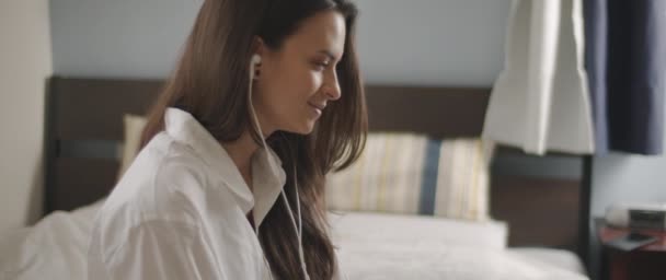 Zamknij Młodą Kobietę Rozmawiającą Kimś Przez Słuchawki Siedząc Łóżku Praca — Wideo stockowe