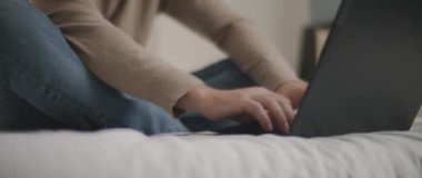 Adam yatak odasındaki dizüstü bilgisayarda bir şey yazıyor. Yavaş çekim, sığ alan derinliği, BMPCC 4K