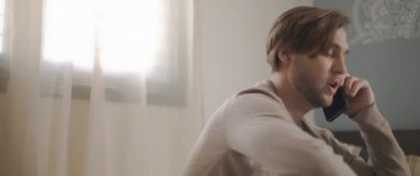 Evden bir dizüstü bilgisayarla çalışırken telefonla konuşan bir adam. Ağır çekim, yakın çekim. BMPCC 4K