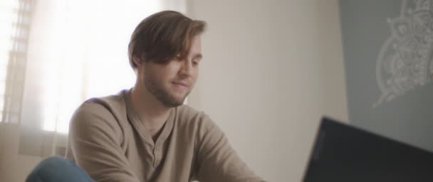 Close Young Man Smiling While Sitting Bed Working Computer Slow — Stock Video