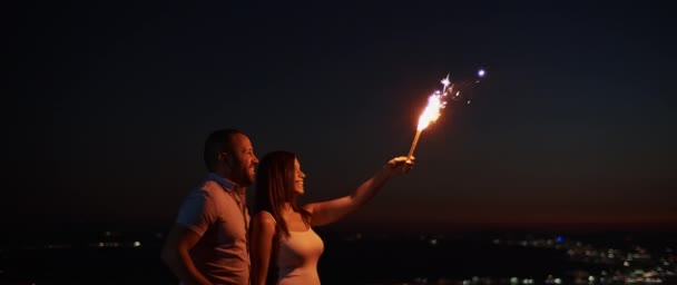 Young Couple Holding Firework Hill Night Bokeh City Lights Background — Stock Video