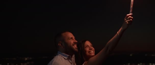 Młoda Para Uśmiechnięta Podczas Trzymania Fajerwerków Wzgórzu Nocy Bokeh Światła — Wideo stockowe