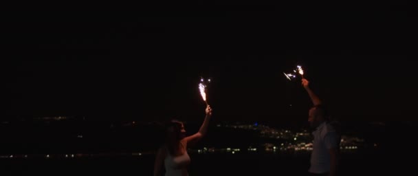 Young Couple Jumping Having Fun Enjoy Celebrating While Holding Fireworks — Stock Video