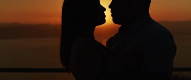 Gün batımında kucaklaşan genç bir çiftin romantik bir akşam geçirmesini. Yavaş çekim.  