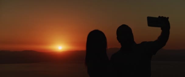 Silhueta Jovem Casal Tirando Uma Selfie Pôr Sol Com Lago — Vídeo de Stock