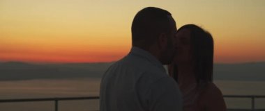 Gün batımında öpüşen genç bir çiftin yakın çekimi. Romantik bir akşam geçiriyoruz. Ark atışı, yavaş çekim.. 