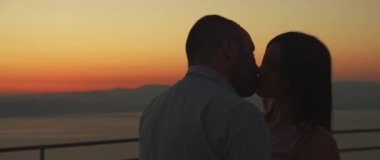 Gün batımında öpüşen genç bir çiftin yakın çekimi. Romantik bir akşam geçiriyoruz. Ark atışı, yavaş çekim.. 