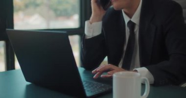 Telefonda konuşurken dizüstü bilgisayarla çalışan bir iş adamının fotoğrafını çek. İzleme çekimi, yavaş çekim.. 