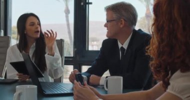 Genç bir yaratıcı iş ekibi, bir ofis toplantısı sırasında proje fikirlerini birbirleriyle paylaşıyorlar. Yavaş çekim.