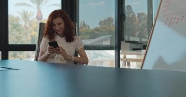 Ofisinde otururken gülümseyen bir iş kadınının orta boy fotoğrafı. Yavaş çekim.