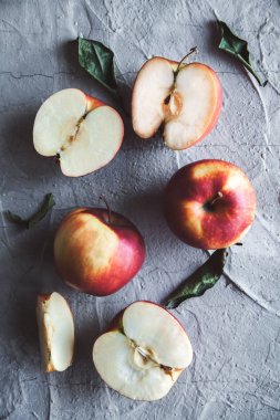 Elma, bütün ve yaprakları ile dilimlenmiş. Rustik taş masanın üstünde. Üstten görünüm