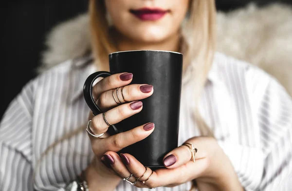 Weibliche Hände mit einer weißen Tasse Tee, weinroter Maniküre, das Mädchen trägt ein Hemd — Stockfoto