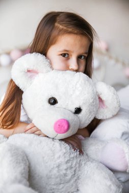 Küçük kız yatakta oturmuş ona teddy ile. Ev, konfor, Aile, ilişkiler, insanlar