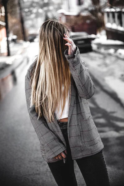 Chica atractiva en una chaqueta y camiseta blanca caminando por la calle . — Foto de Stock