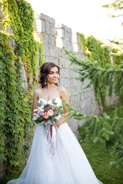 Mooie jonge bruid met een boeket van bruiloft bloemen. Vakantie jurk — Stockfoto