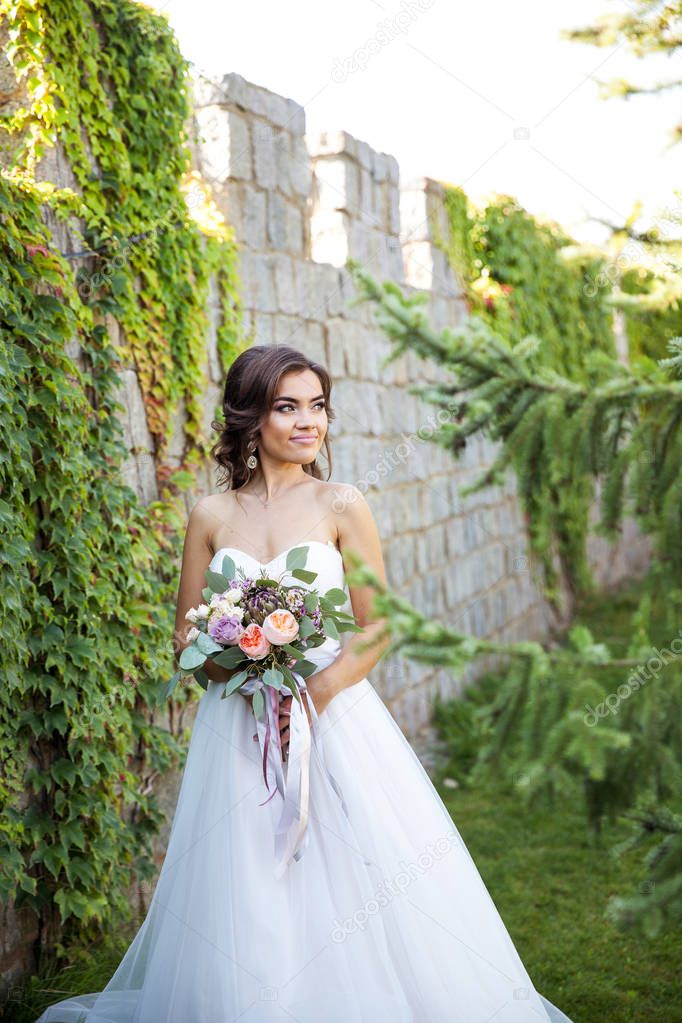 Beautiful young bride with a bouquet of wedding flowers. Holiday dress
