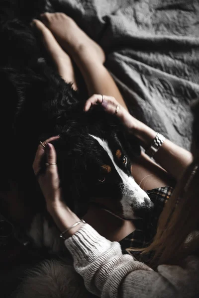 Bella ragazza sdraiata e il suo cane carino Bernese Mountain Dog sul letto, elegante, alla moda, accogliente — Foto Stock