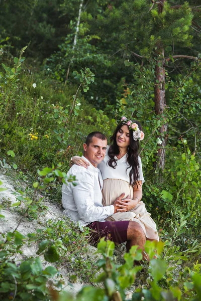 Jovem grávida com o marido desfrutando da natureza vestindo jeans casuais e estilo e camiseta branca . — Fotografia de Stock