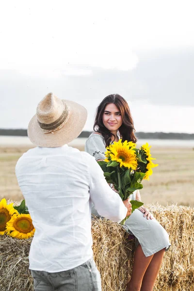Pregnant with her husband in the manger. Beautiful couple with sunflowers — Stock Photo, Image