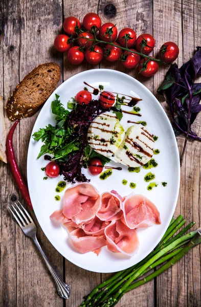 Appetizing dish of meat and cheese with greens on a wooden background