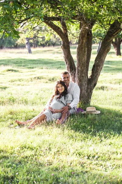 Happy pregnant woman with her husband at sunset — Stock Photo, Image