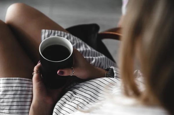 Mains féminines tenant une tasse de thé blanc, manucure bordeaux, la fille est habillée d'une chemise — Photo