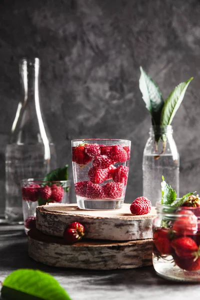 Jordgubbar i vatten på en mörk grå bakgrund. Hälsosam mat, frukt. En bukett blommor som dekoration — Stockfoto