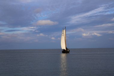 Gölün üzerinde dramatik bir gökyüzü, bir yelkenli teknesi ve Nida 'da şirin bir lig evi, Curonian Spit, Litvanya