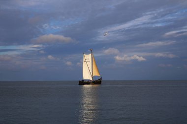 Gölün üzerinde dramatik bir gökyüzü, bir yelkenli teknesi ve Nida 'da şirin bir lig evi, Curonian Spit, Litvanya