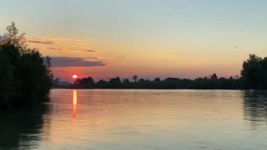 Saf doğada el değmemiş nehrin üzerinde muhteşem turuncu gün batımı.