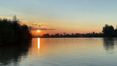 Saf doğada el değmemiş nehrin üzerinde muhteşem turuncu gün batımı.