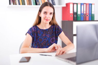 Parlak ofisinde oturan ve dizüstü bilgisayar kullanarak genç kadın