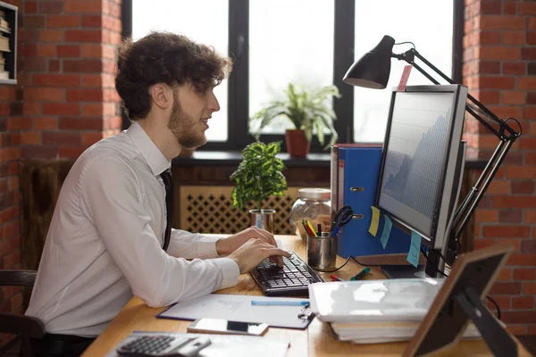 Bilgisayarda çalışan genç gülümseyen iş adamı