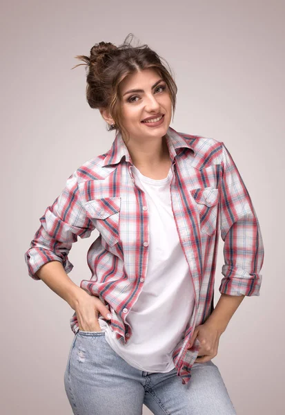 Ritratto di giovane donna sorridente in camicia a quadri e t-shirt bianca, in piedi con le braccia in tasca — Foto Stock