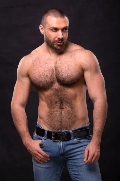 Acımasız kas üstsüz adam, kot pantolon. Ayakta rahatlatıcı vücut geliştirmeci.