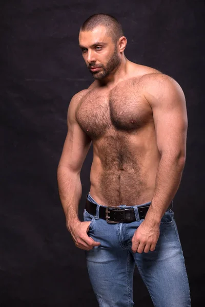 Acımasız kas üstsüz adam, kot pantolon. Ayakta rahatlatıcı vücut geliştirmeci.
