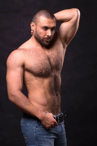 Acımasız kaslı adam, kot pantolon. Tioless vücut geliştirmeci ayakta poz.