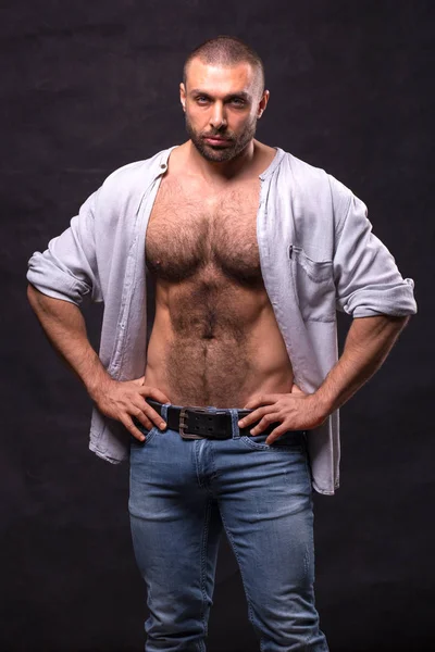 Uomo muscoloso brutale, in jeans e camicia di cotone. Culturista rilassante in piedi . — Foto Stock
