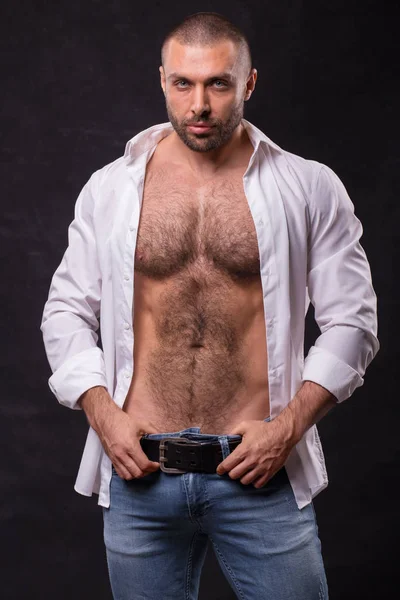 Acımasız kaslı adam, kot pantolon ve pamuklu gömlek. Ayakta rahatlatıcı vücut geliştirmeci.