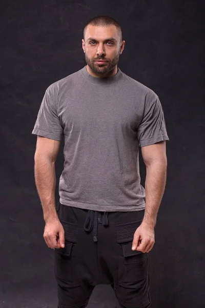 Przystojny mięśni broda człowiek stojący w studio nad ciemnym tle — Zdjęcie stockowe