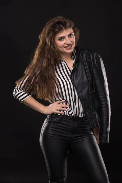 Portrait of smiling caucasian young woman in leather clothes pose over black background. — Stock Photo, Image