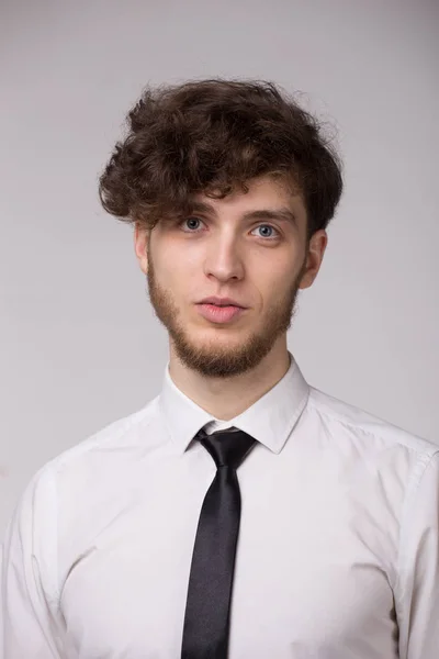 Gömlek gülümseyen ve gri arka plan üzerinde kamera bakarak emin genç adam