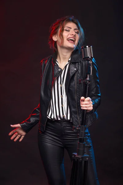 Портрет исполнителя экспрессивного рока в кожаной куртке и с микрофоном в стиле ретро . Стоковая Картинка