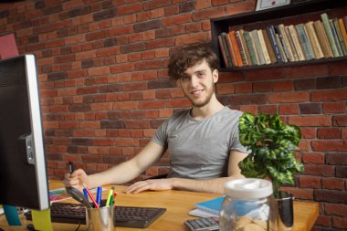 İş yerinde çalışan genç gülümseyen dijital sanatçı çatı katı tarzında arkadaş canlısı görünüyor..