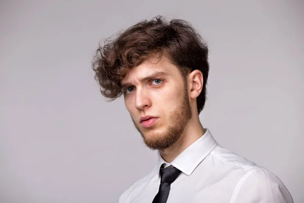 Üzgün ve üzgün olan, gri arka plan üzerinde duran, üzüntü ve olumsuz duyguları ifade şüpheci genç adam Stüdyo portre