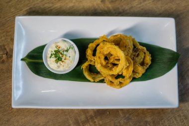 Ekşi kremayla servis edilen kızarmış soğan halkası..