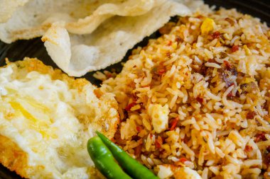 Baharatlı pilav, kurutulmuş biber, kızarmış yumurta ve balık krakeri..