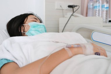 Genç kadın hasta yakından intravenöz normal salin ile hastane yatağında yatıyordu