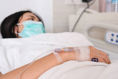 Genç kadın hasta yakından intravenöz normal salin ile hastane yatağında yatıyordu