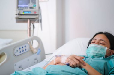 Genç kadın hasta yakından intravenöz normal salin ile hastane yatağında yatıyordu
